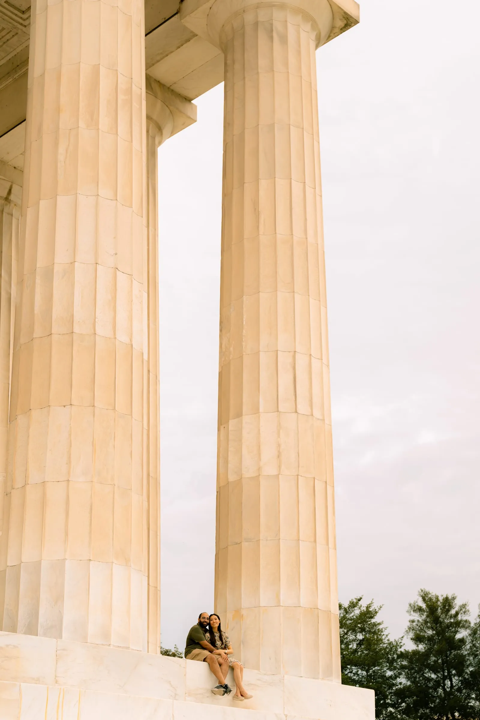 Maryann and Samuel sitting together, tiny beneath the Lincoln Memorial's towering columns
