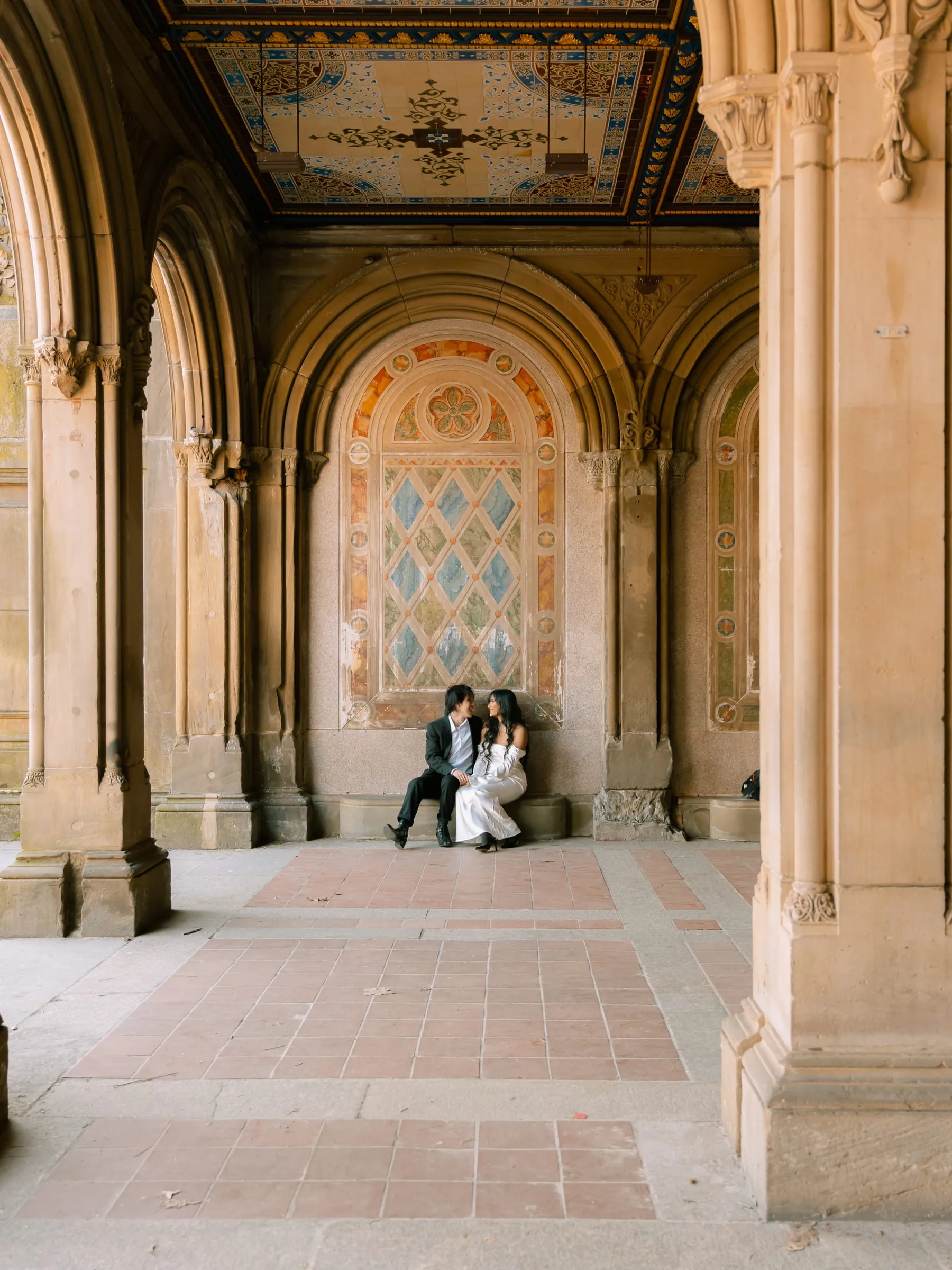 Noushin and Nathan sitting together beneath the painted stone arches of Bethesda Terrace in Central Park