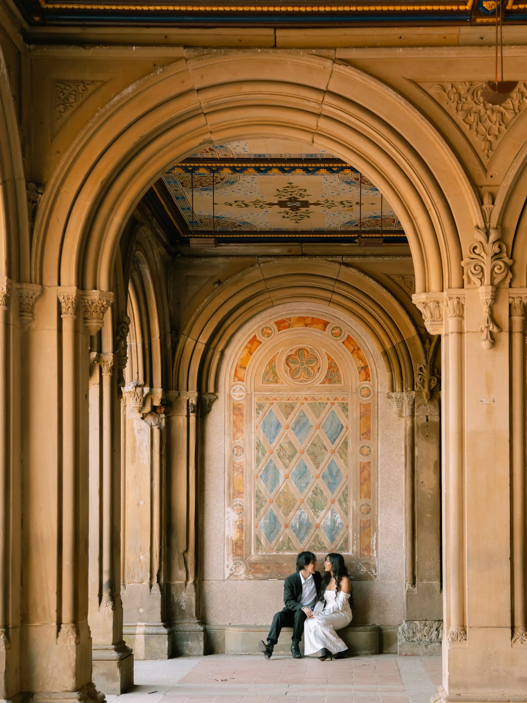A wide view of Noushin and Nathan seated under the arcade's ornate tiled ceiling