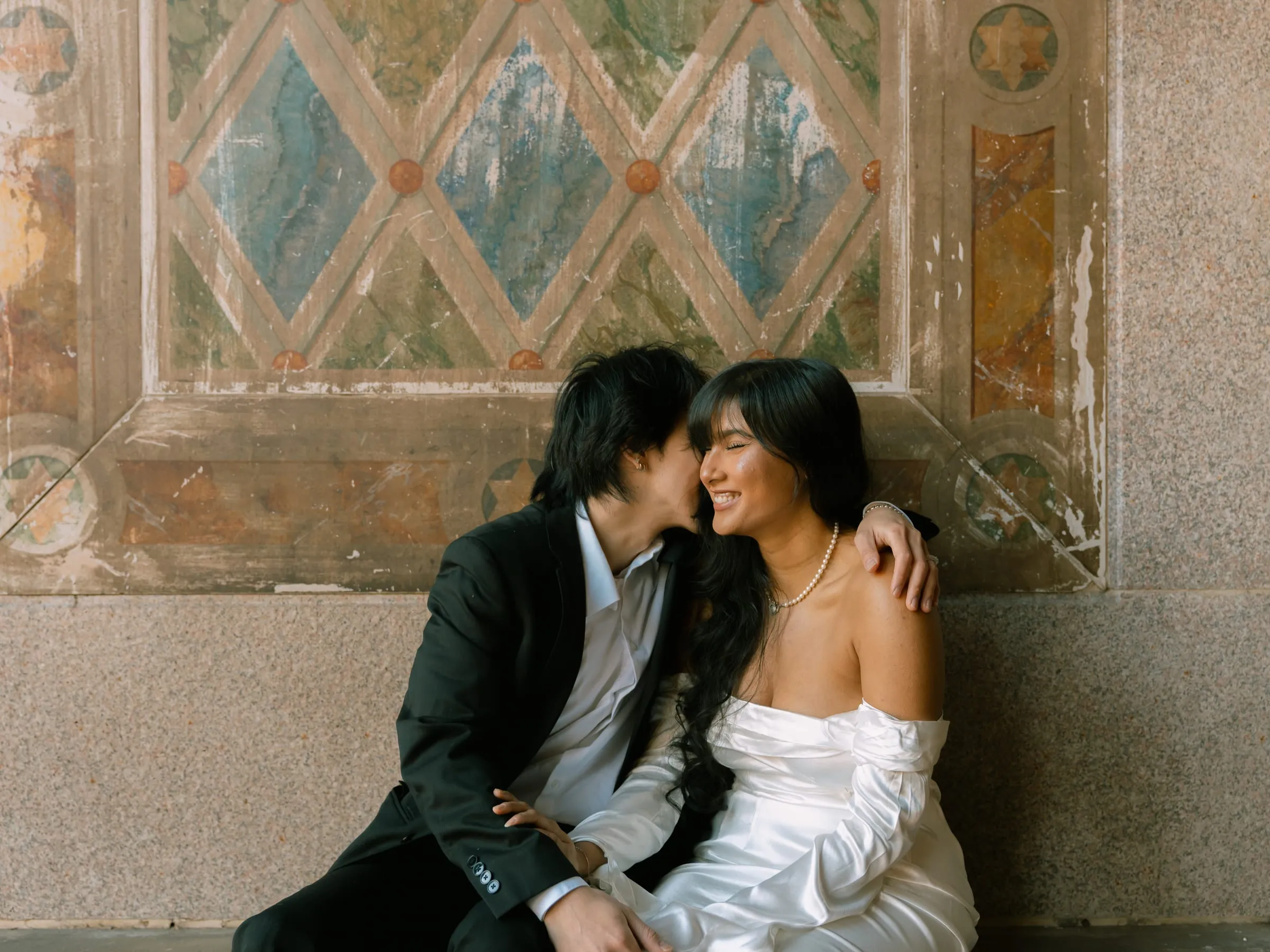 Close-up of Noushin and Nathan embracing, her pearl necklace catching the light