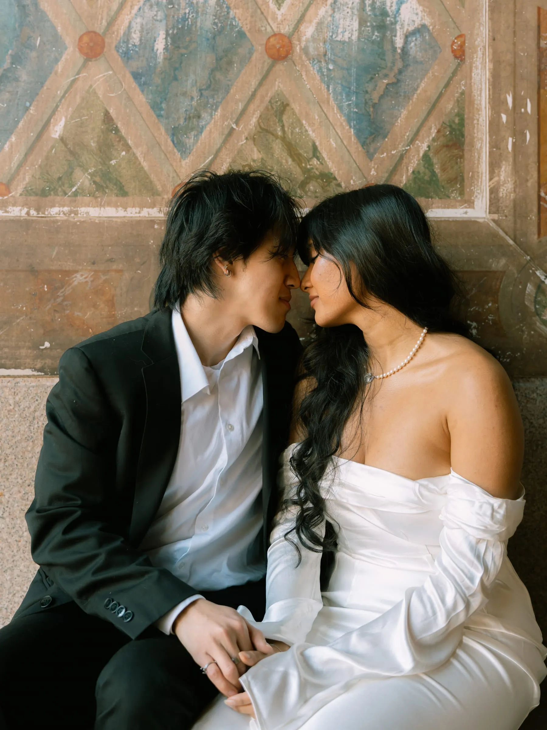 Noushin and Nathan with foreheads touching in a quiet moment under the arcade