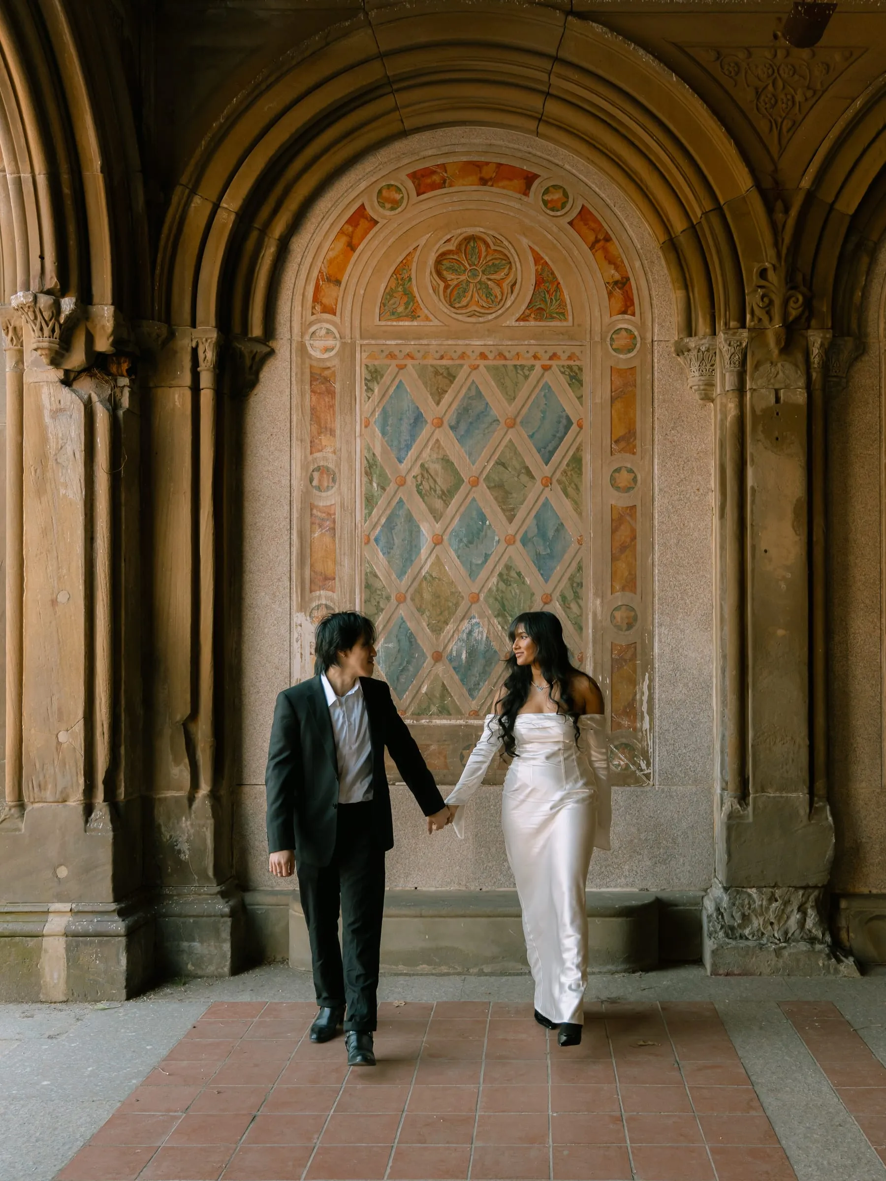 Noushin and Nathan walking together beneath the arcade's painted arches