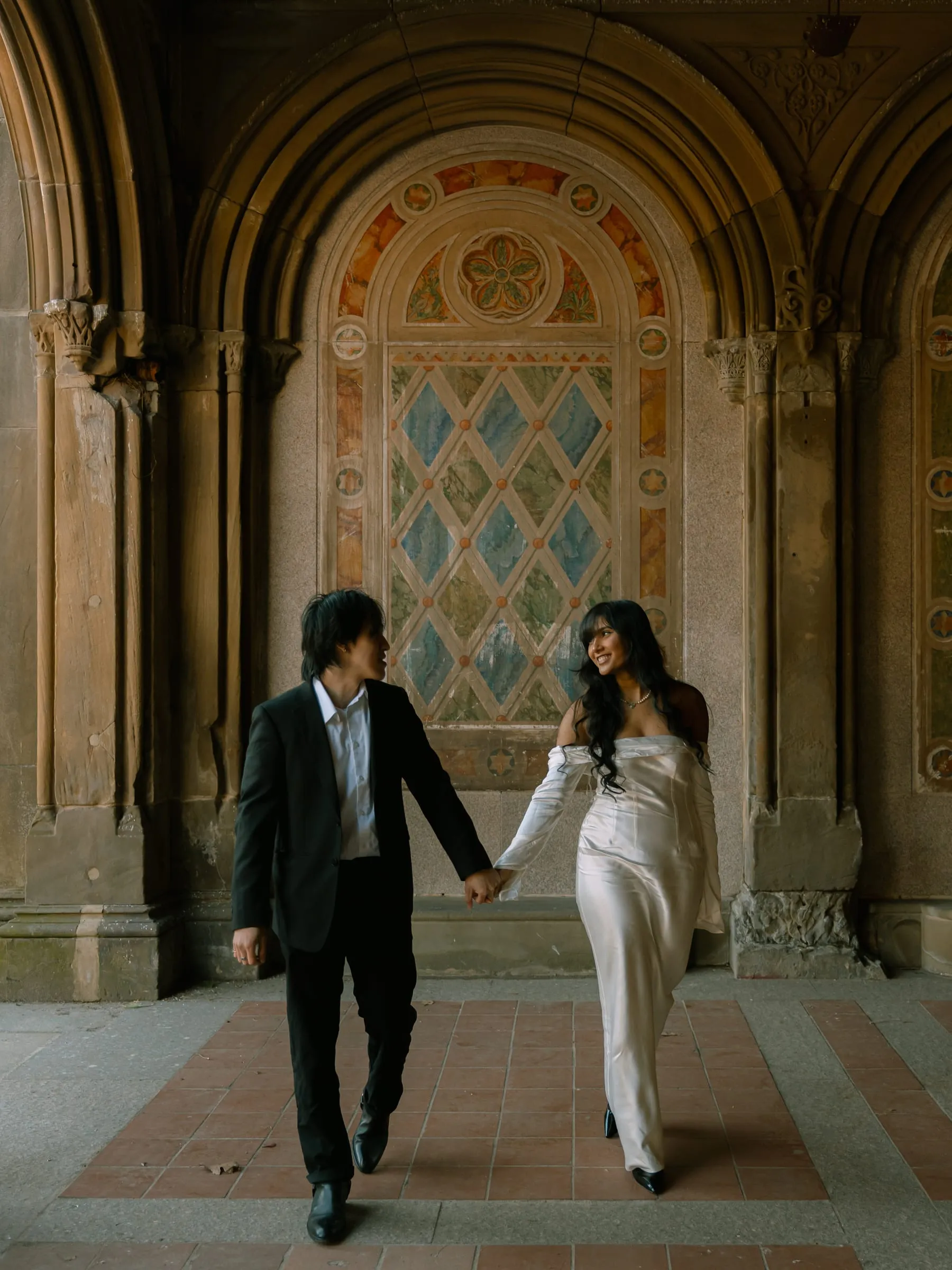 Noushin and Nathan walking hand in hand through the Bethesda Terrace arcade