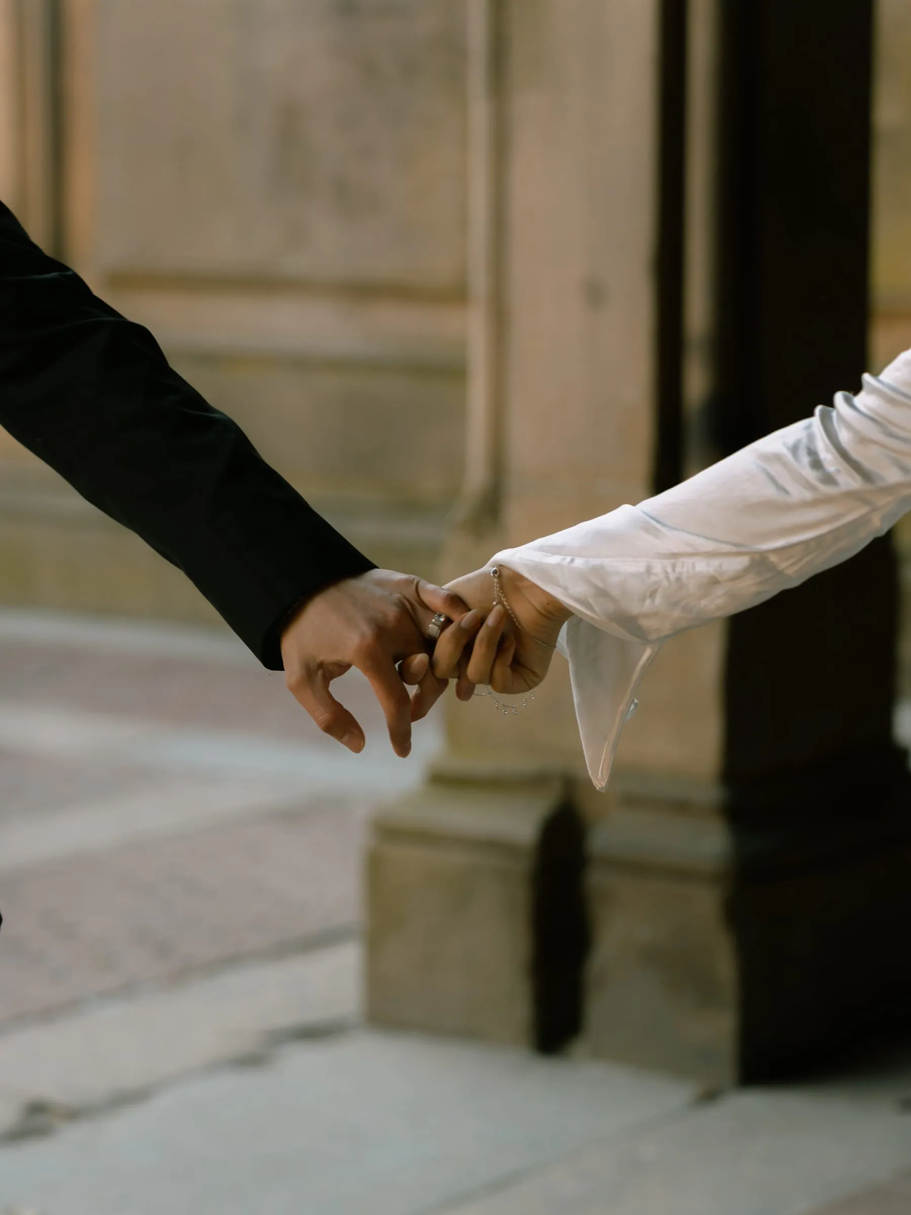 Close-up of Noushin and Nathan's hands reaching for each other in the arcade