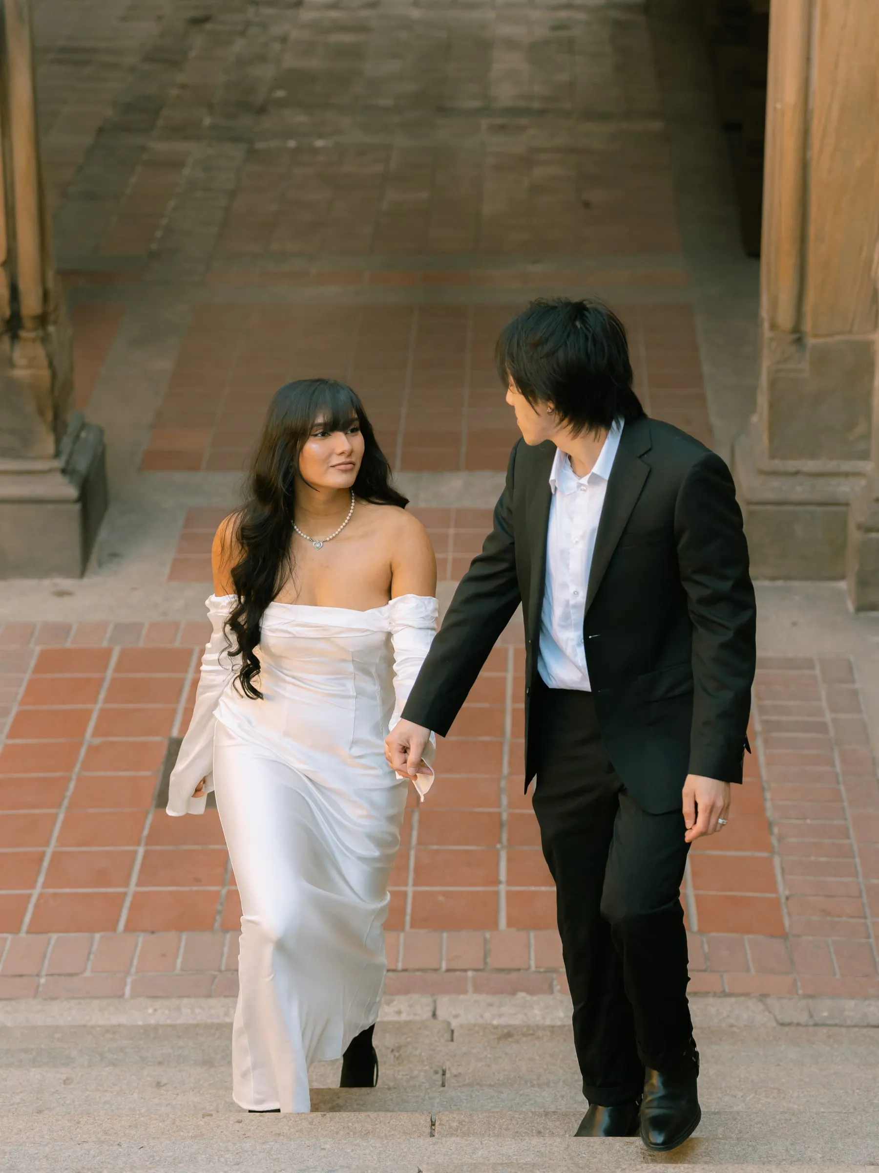 Noushin and Nathan walking hand in hand up the steps of Bethesda Terrace