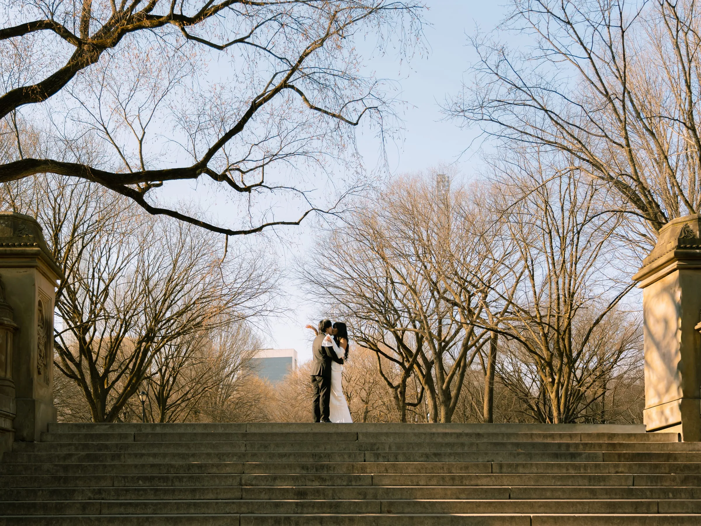 Noushin and Nathan sharing a kiss silhouetted against the bare winter trees
