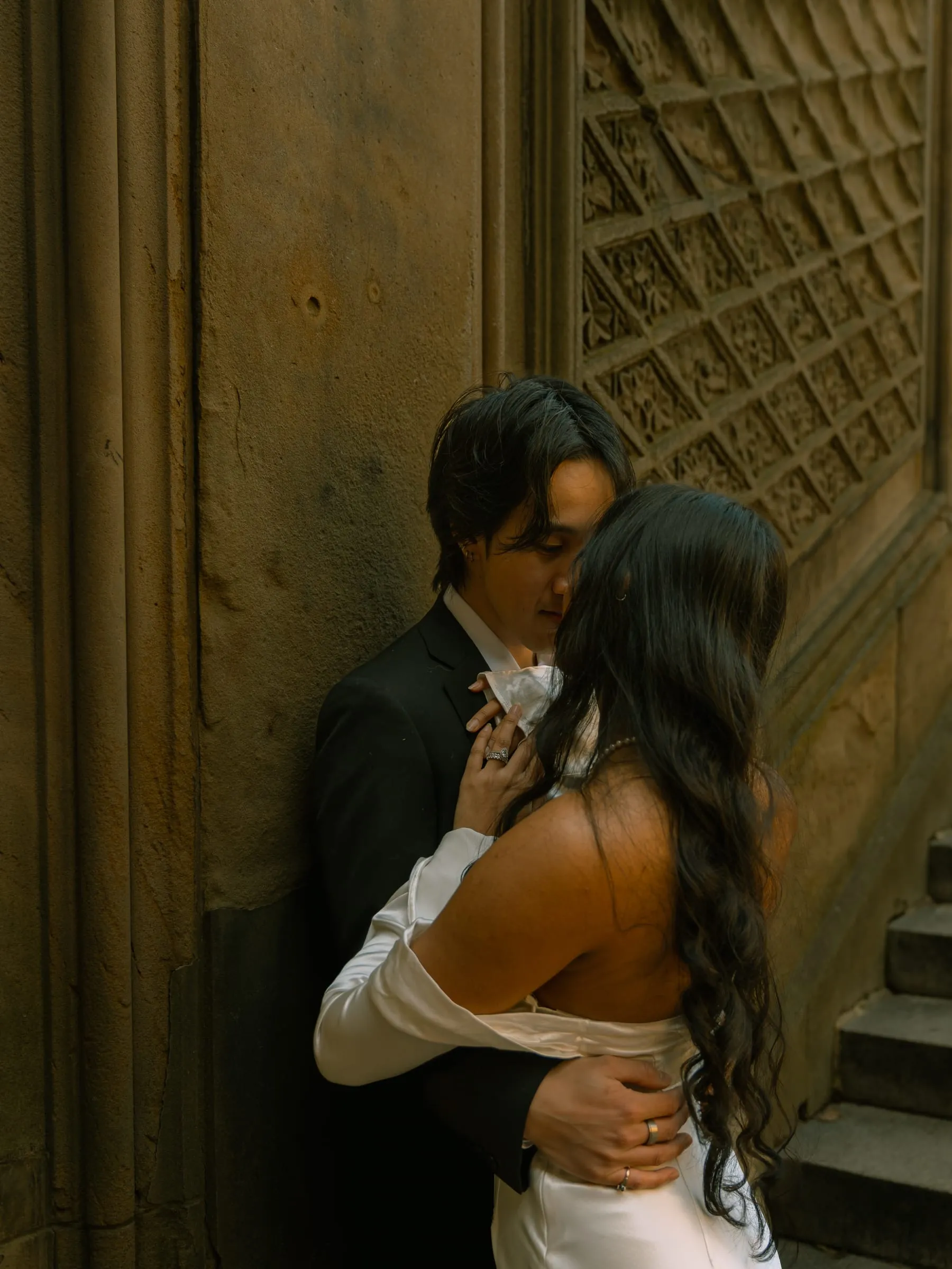 Noushin and Nathan embracing against Bethesda Terrace's carved stone wall