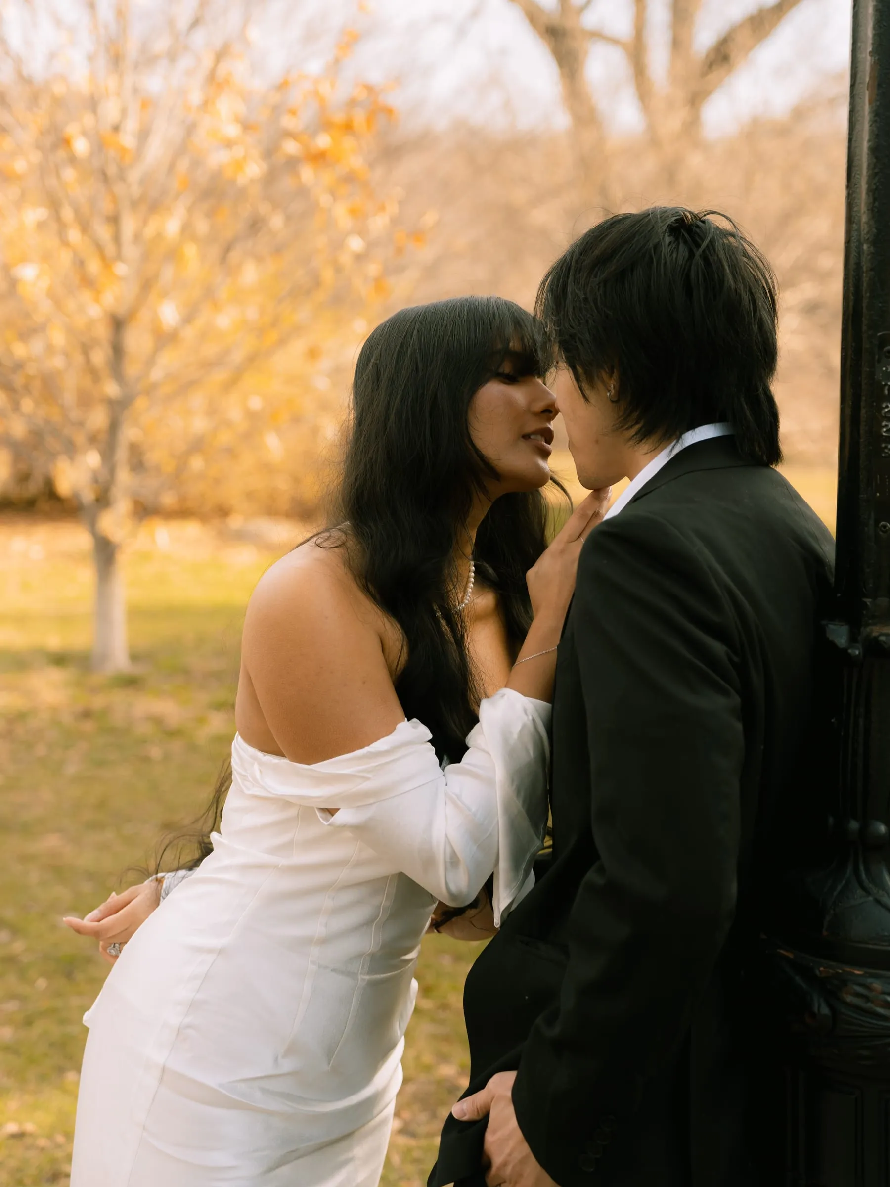 Noushin and Nathan leaning in for a kiss beside a lit lamppost in the golden hour light