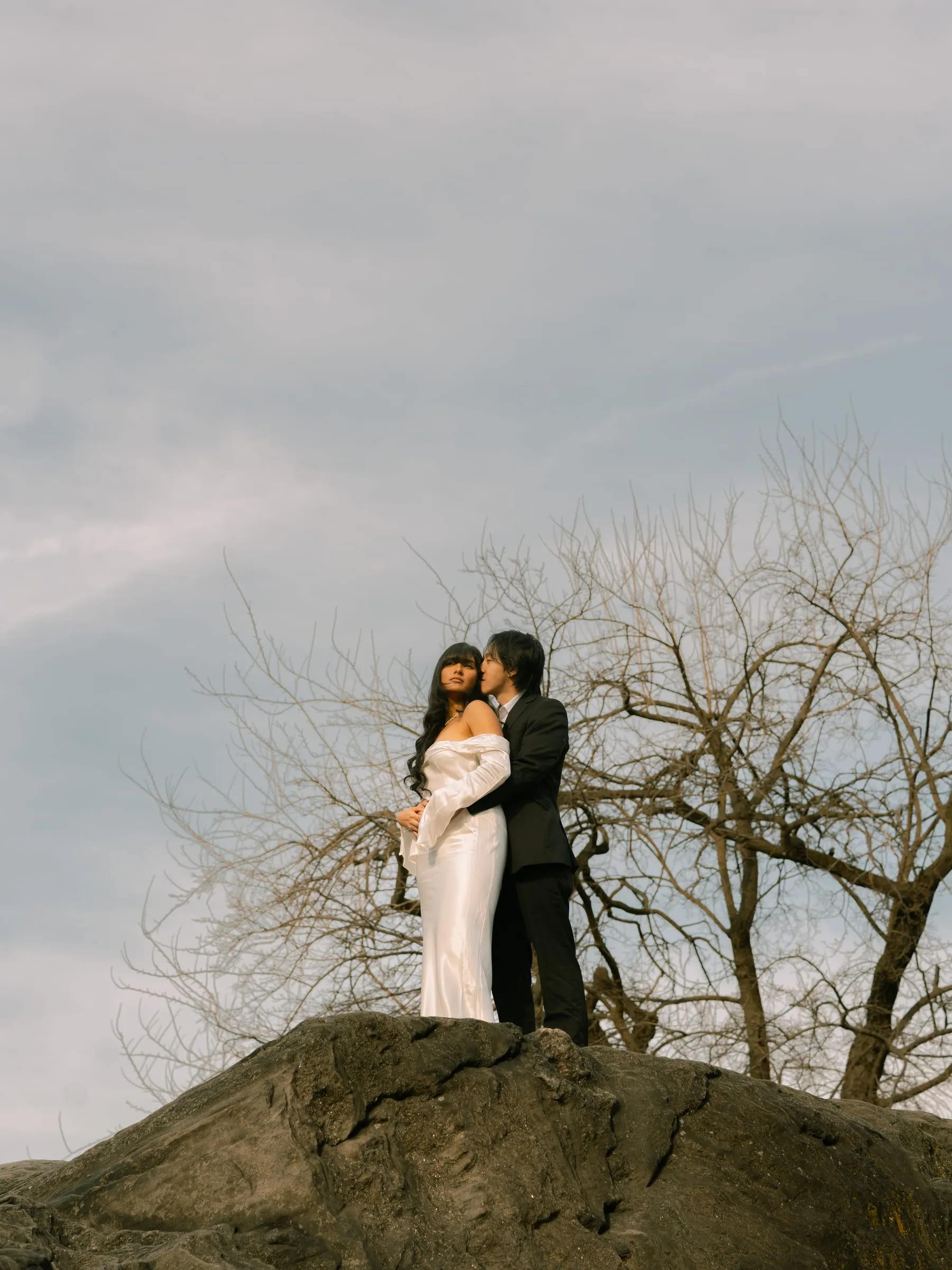 Nathan kissing Noushin's cheek as she laughs atop the rock outcrop
