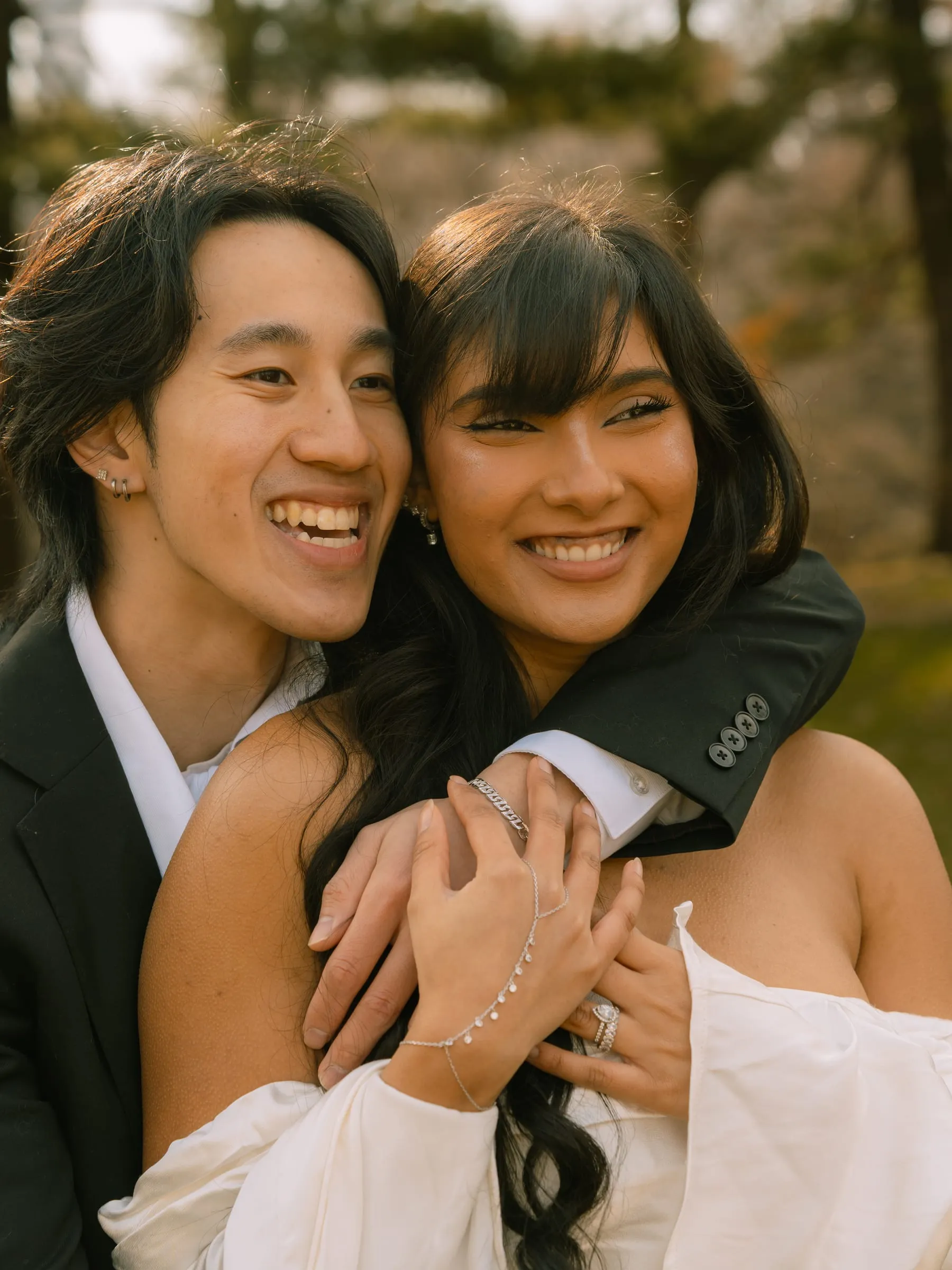 Noushin and Nathan laughing together in a close portrait, his arms wrapped around her