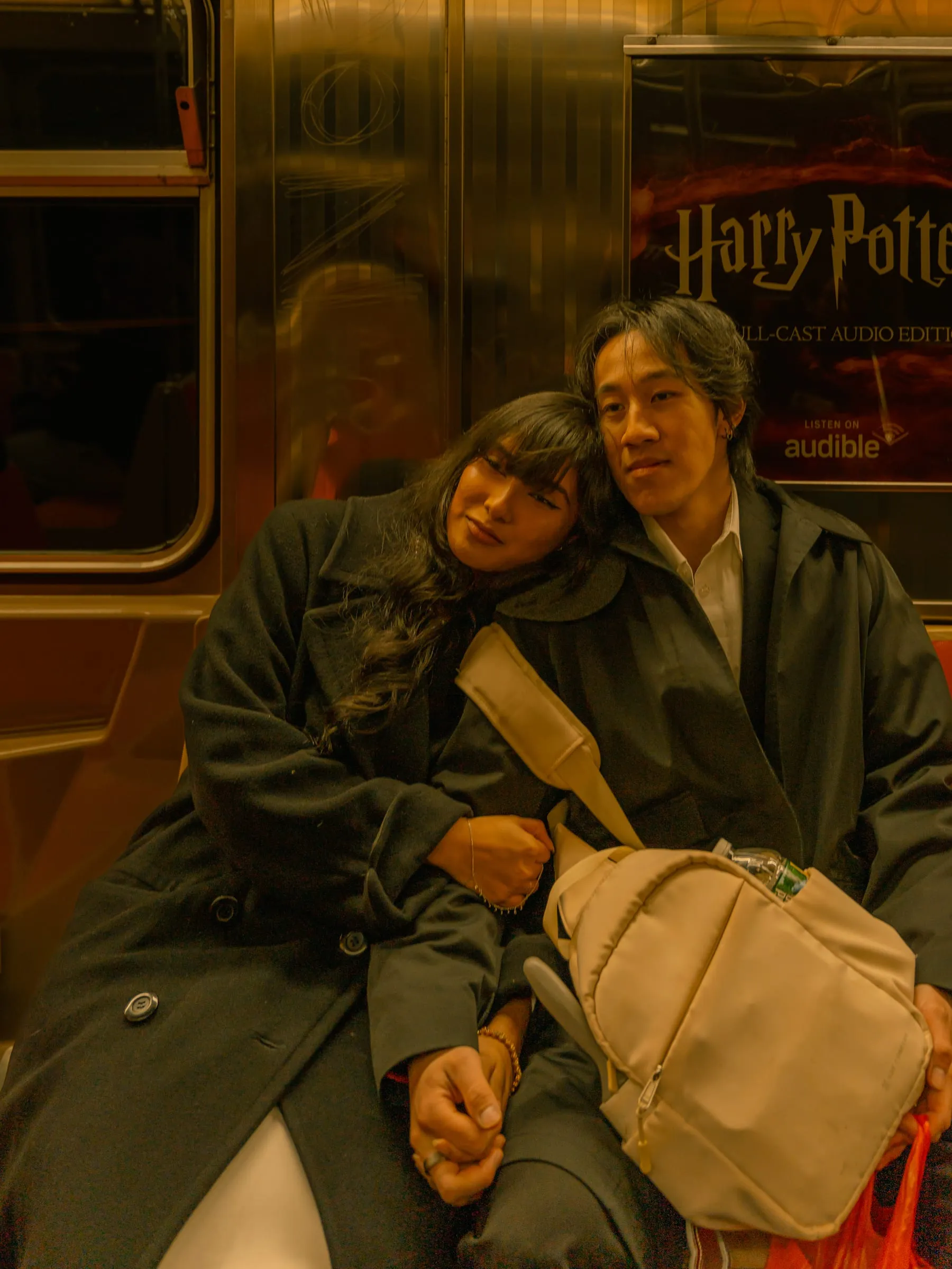 Noushin and Nathan resting against each other on the subway train, riding into the city