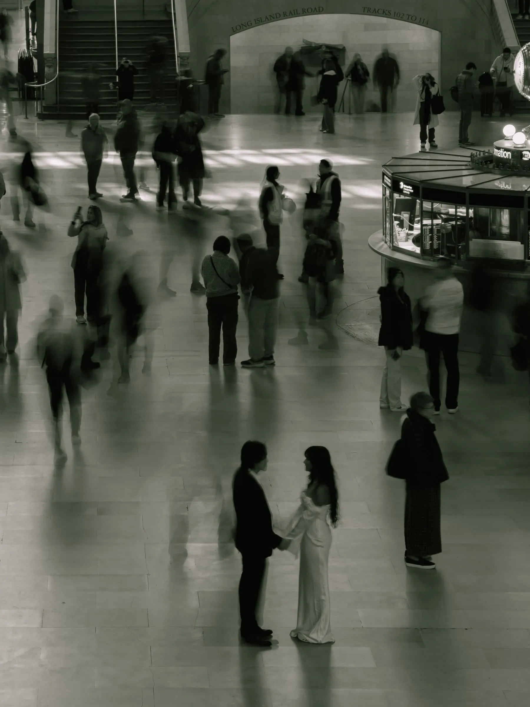 Noushin and Nathan standing together in the middle of Grand Central Terminal's bustling main concourse