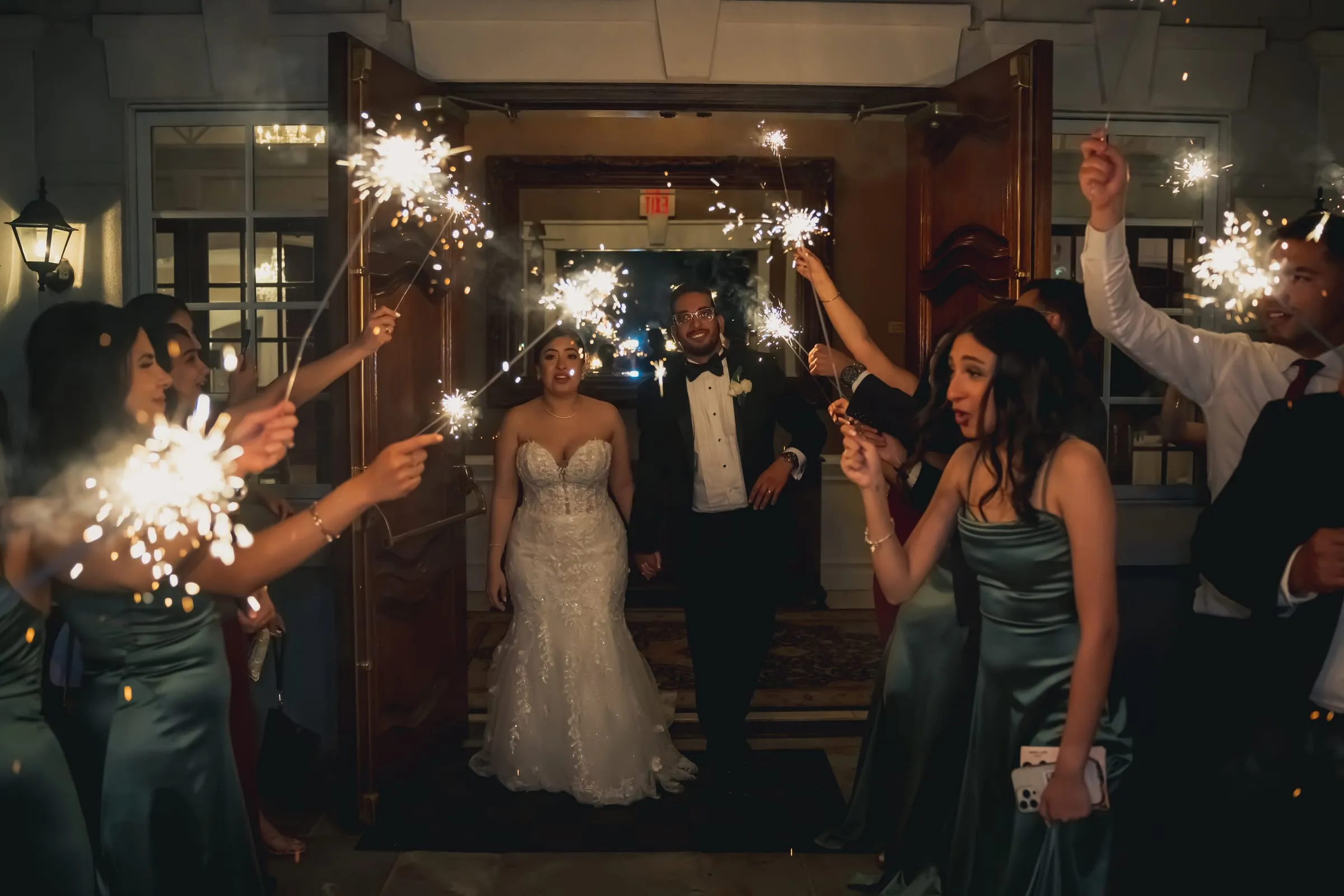 Sandy and Steph stepping through the doors of Foxchase Manor into a tunnel of sparklers