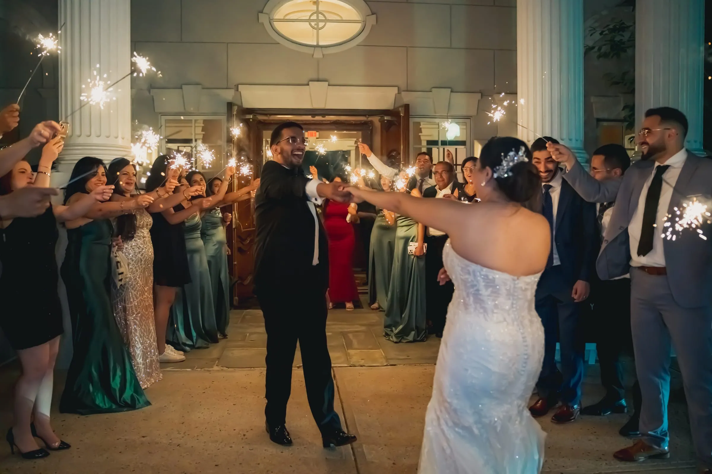 Sandy and Steph reaching for each other's hands in front of the columned entrance