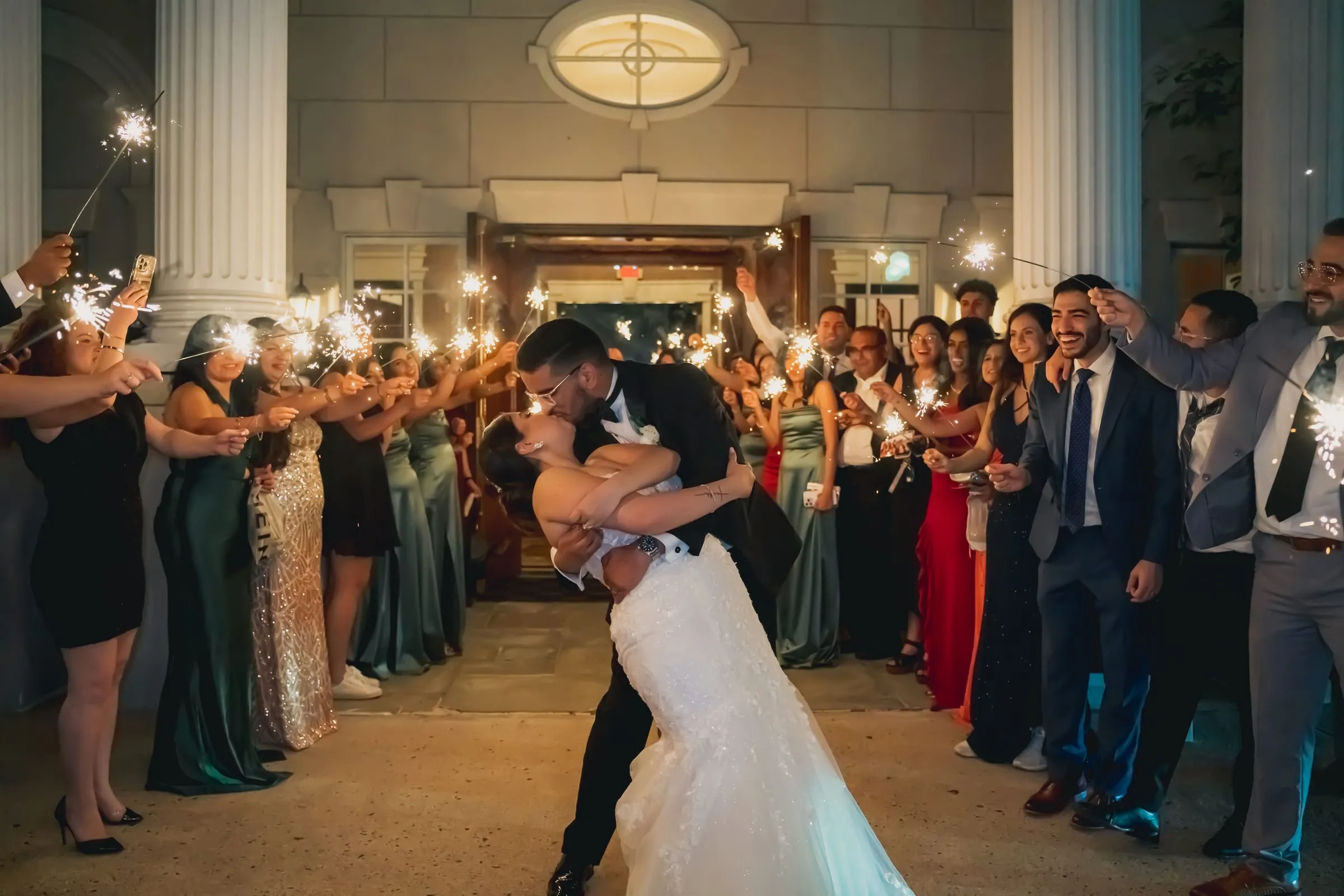 Sandy and Steph kissing in a dip while the guests cheer around them