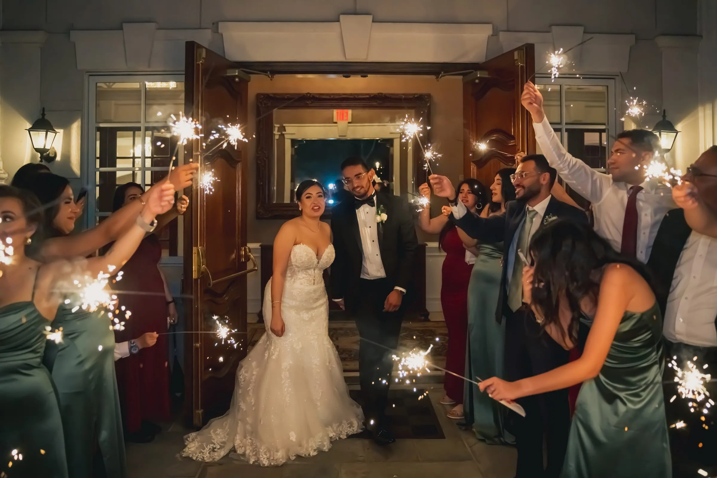 Sandy and Steph framed by the open wooden doors, sparklers glowing around them