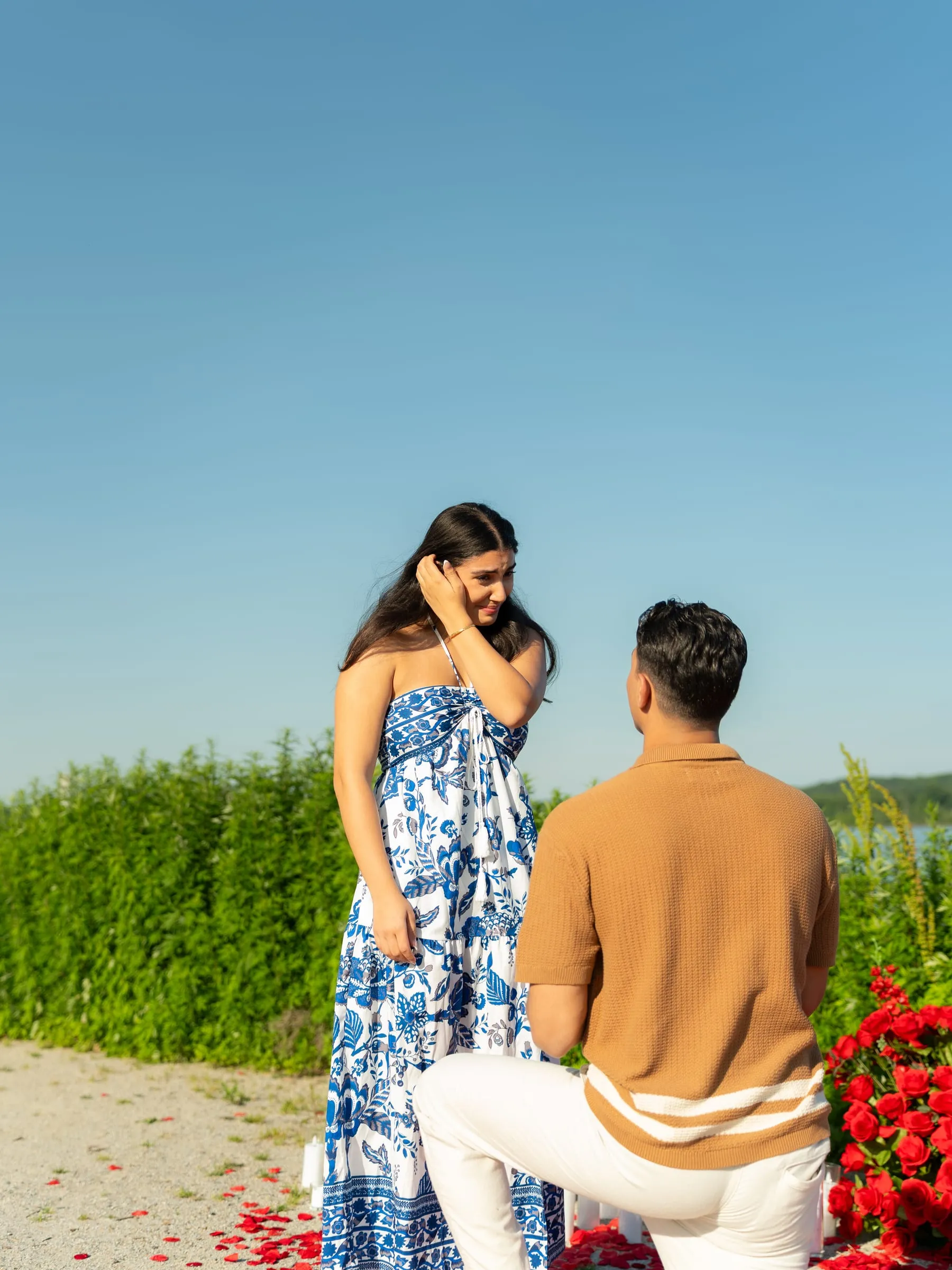 Thomas down on one knee on a path of red rose petals as Verina looks on