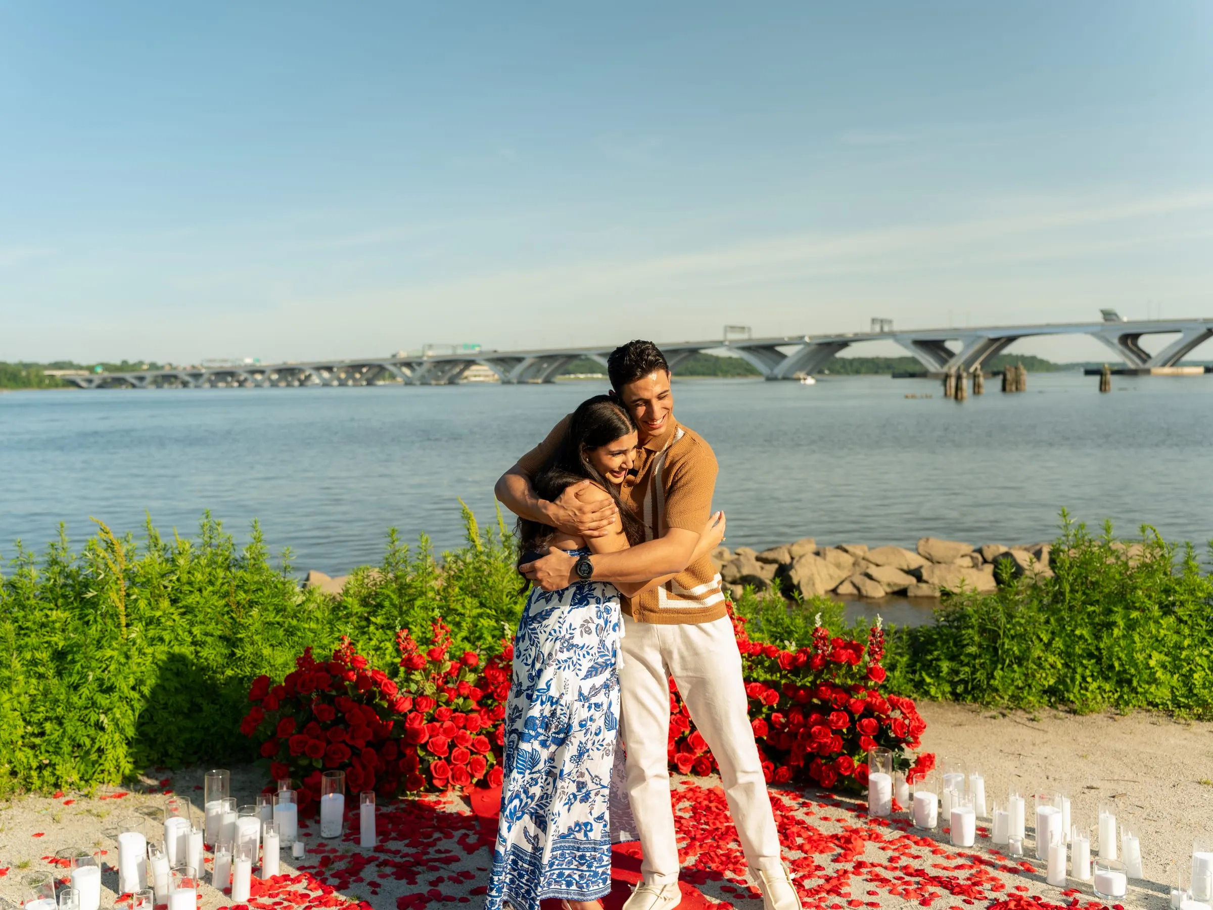 Verina and Thomas embracing after the proposal, the bridge and river behind them
