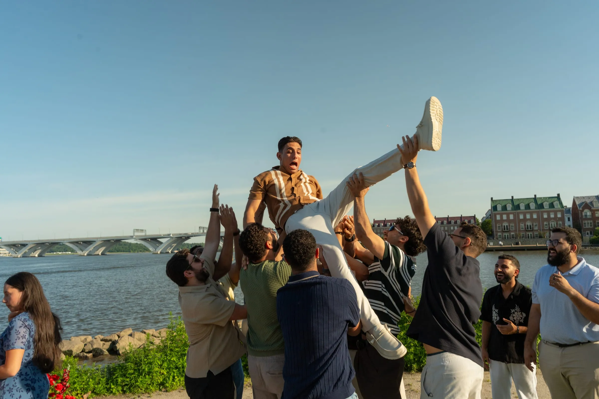 Thomas's friends lifting him overhead as Verina watches, the river and Old Town behind them