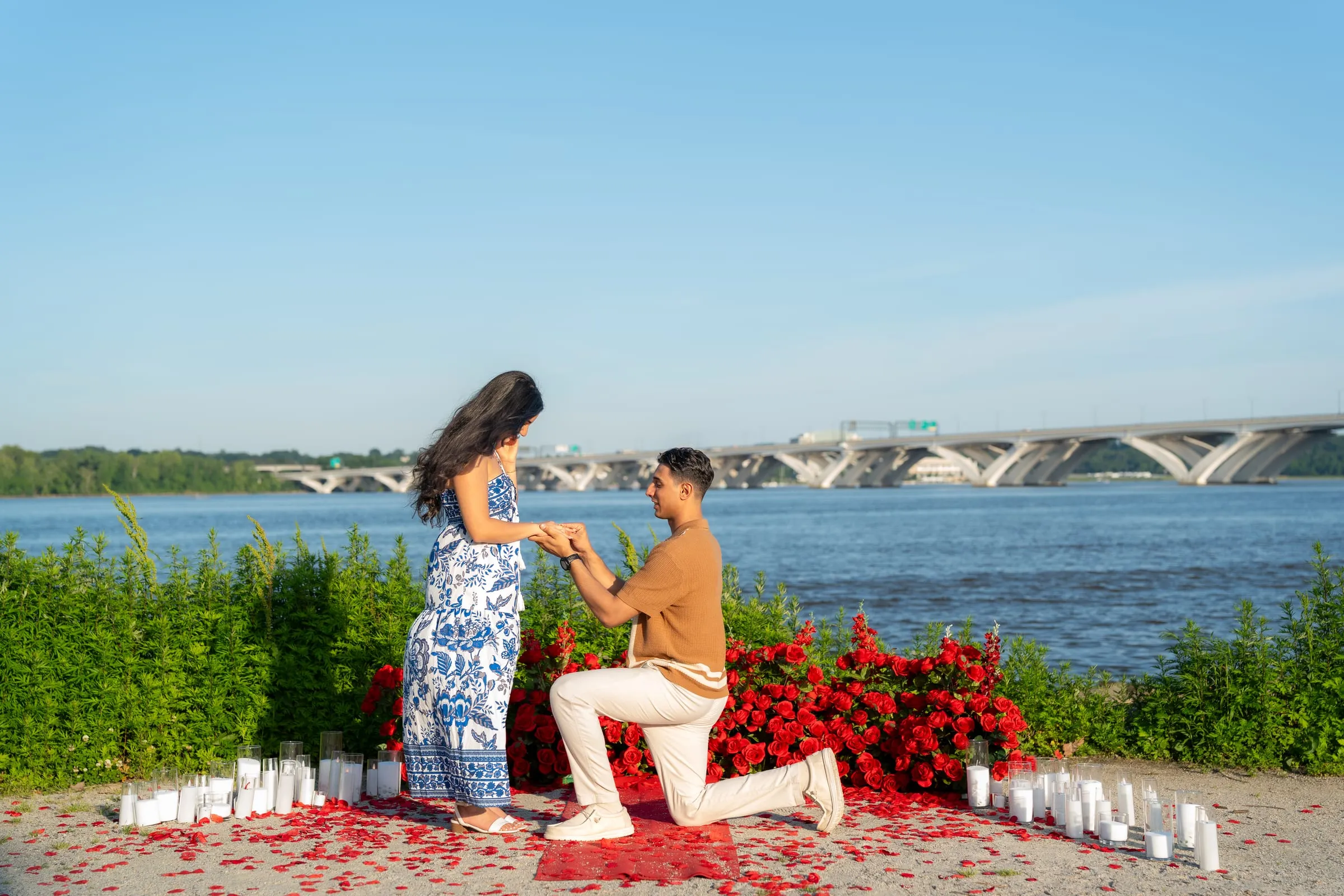 Thomas sliding the ring onto Verina's finger from one knee beside the river