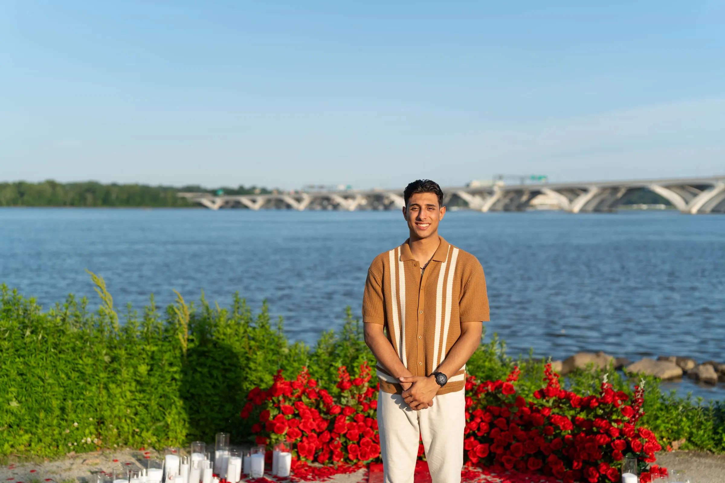 Thomas smiling among the red roses at the proposal site he set up for Verina