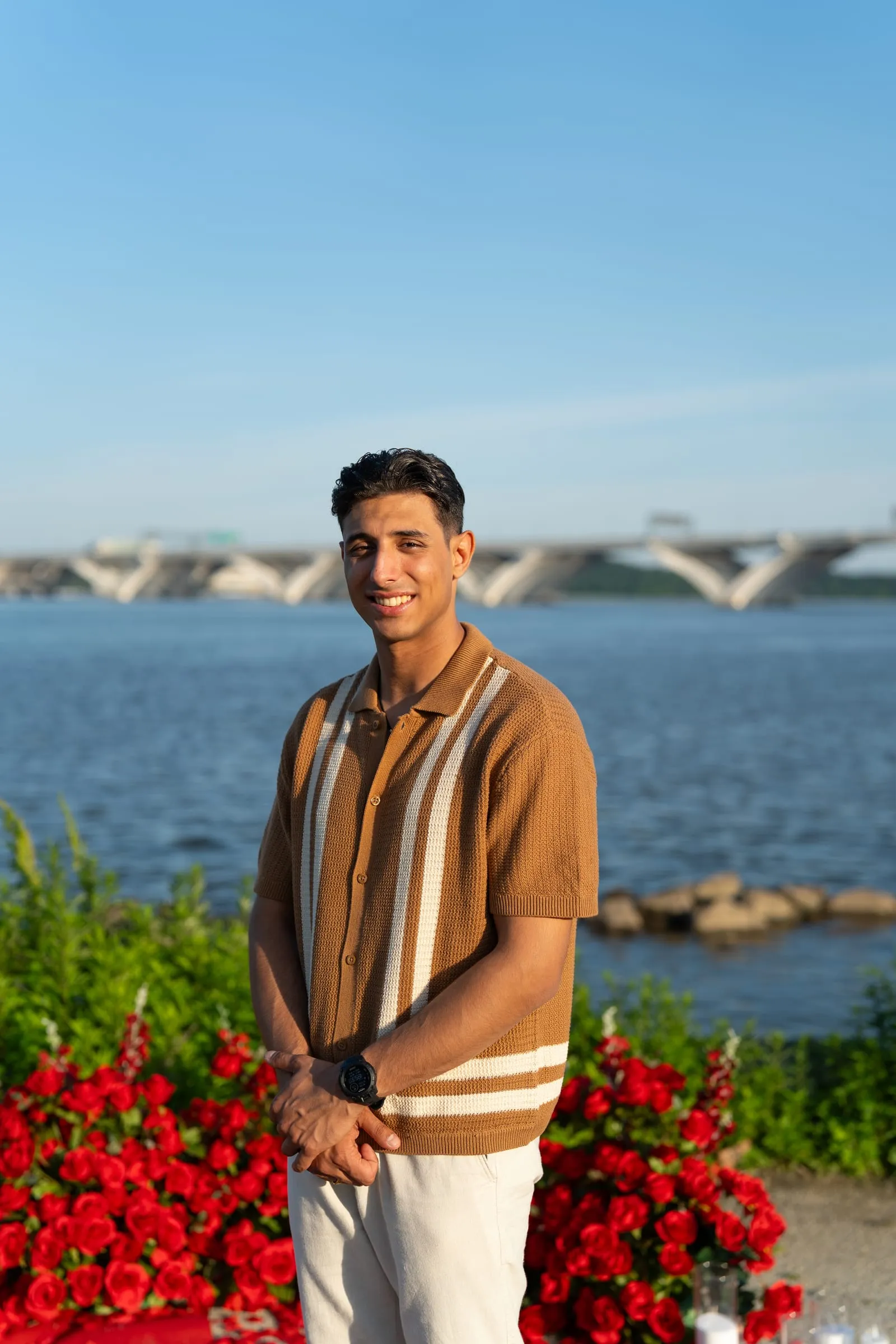 A portrait of Thomas beside the river, with the Woodrow Wilson Bridge in the distance